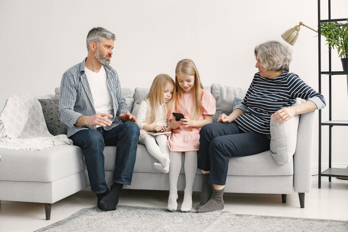 Grandparents and two granddaughters sitting together on a sofa